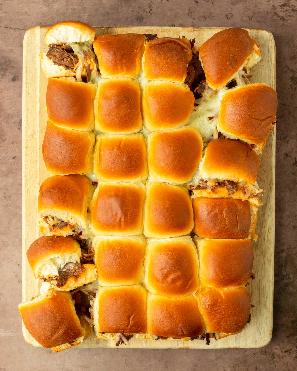 These BBQ pulled beef sliders are an easy and delicious Hawaiian roll pull-apart sandwich made with BBQ pulled beef and mozzarella cheese layered inside perfectly baked Hawaiian rolls for an easy dinner, delicious appetizer and the perfect recipe to serve a crowd.