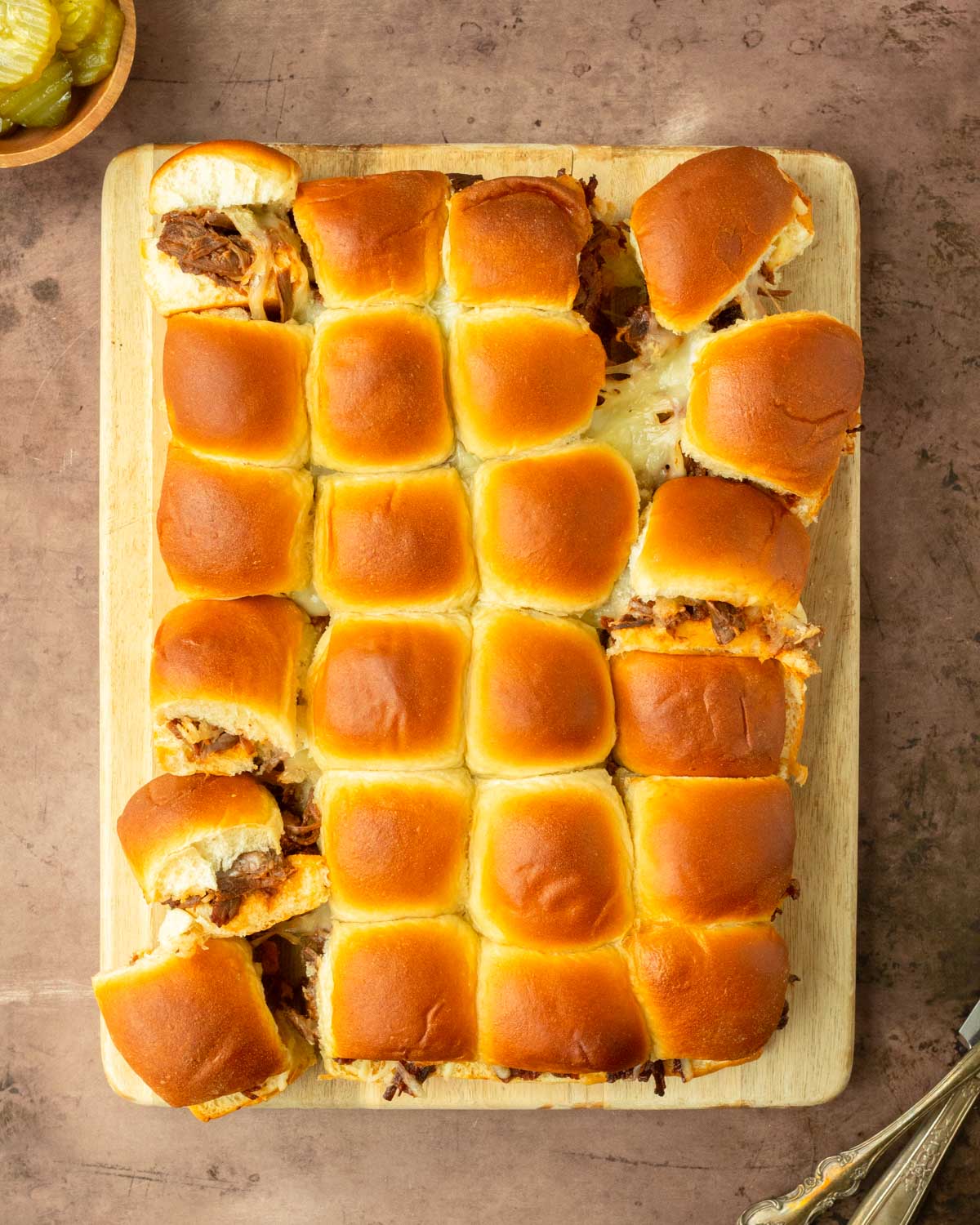 These BBQ pulled beef sliders are an easy and delicious Hawaiian roll pull-apart sandwich made with BBQ pulled beef and mozzarella cheese layered inside perfectly baked Hawaiian rolls for an easy dinner, delicious appetizer and the perfect recipe to serve a crowd.