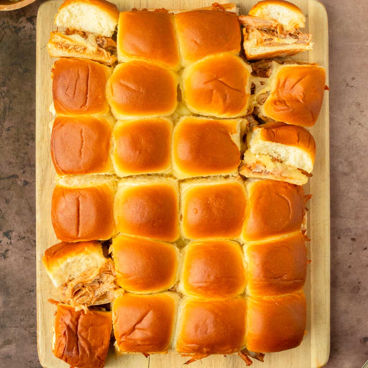 These BBQ pulled pork sliders are an easy and delicious Hawaiian roll pull-apart sandwich recipe made with BBQ pulled pork and Pepper Jack cheese layered inside perfectly baked Hawaiian rolls for an easy dinner, delicious appetizer and the perfect recipe to serve a crowd.